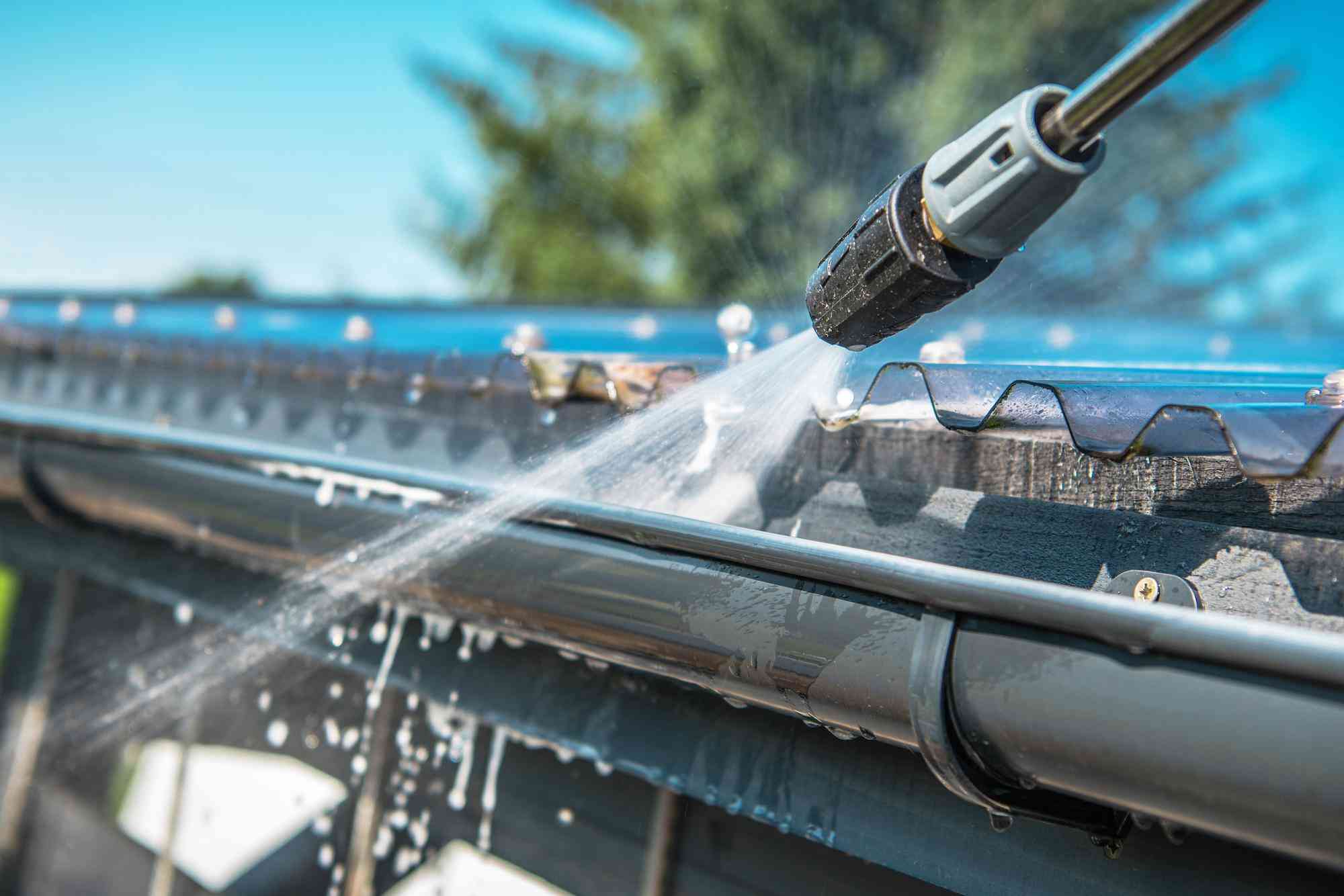 Pressure washer nozzle rinsing out a roof gutter