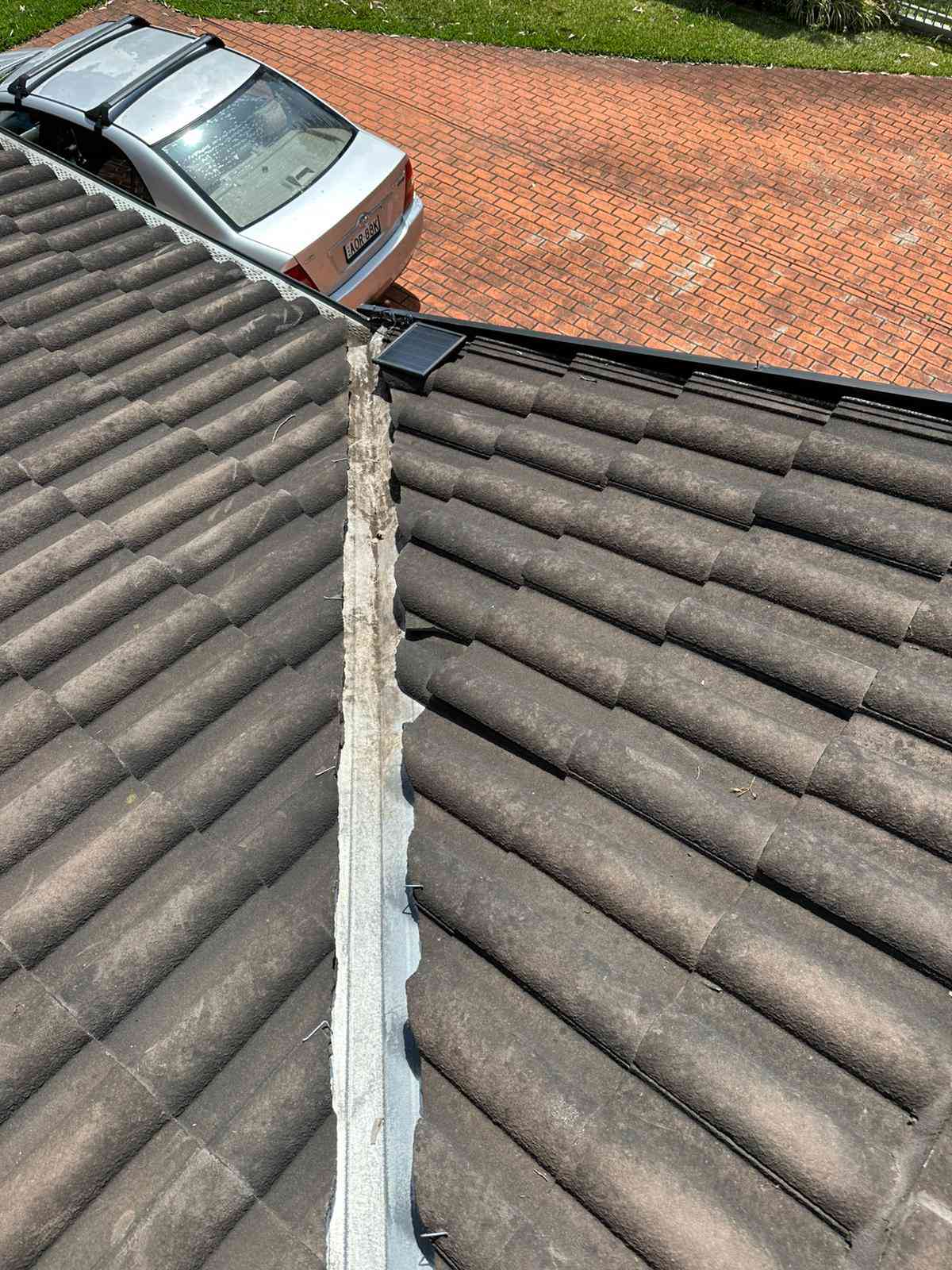 Roof valley cleared of debris above a brick driveway
