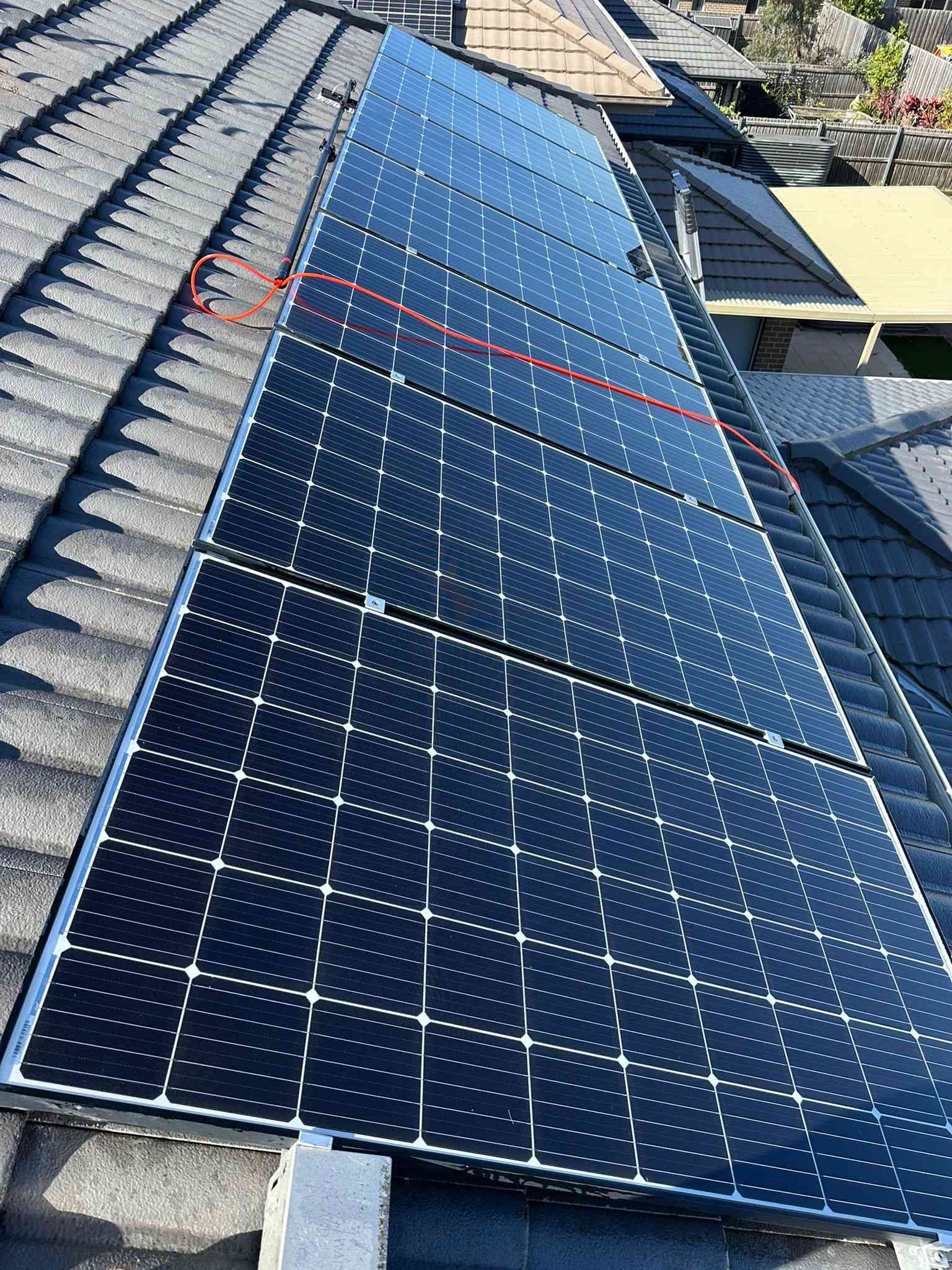 Row of freshly cleaned solar panels on a tiled roof