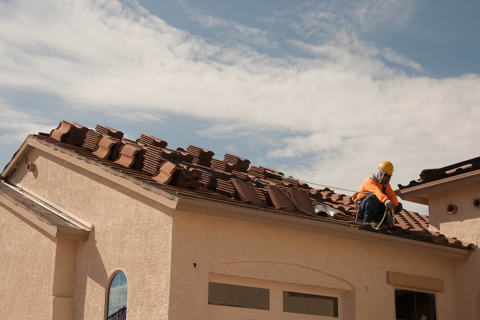 Roofer in a hard hat working on a tiled roof