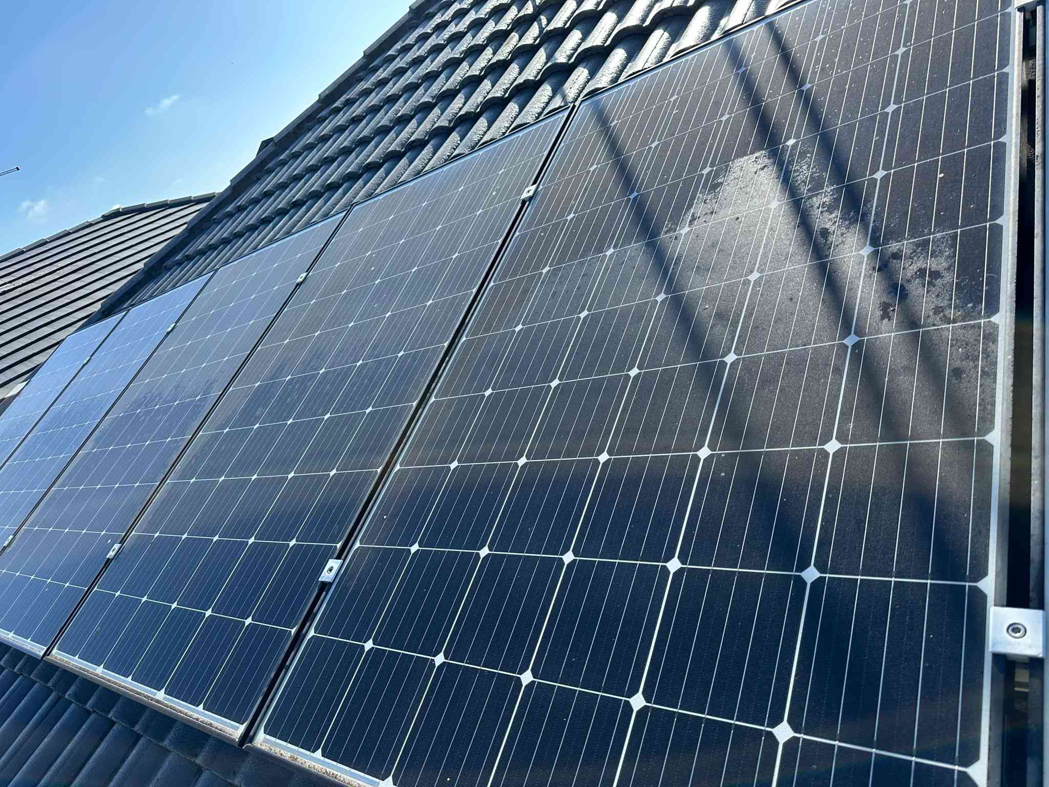 Rooftop solar panels on a tiled roof under a blue sky